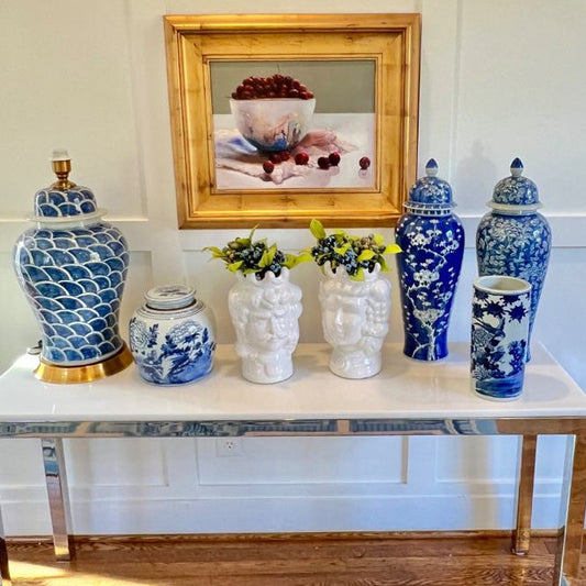 Decorative vases on a table with a framed picture in the background